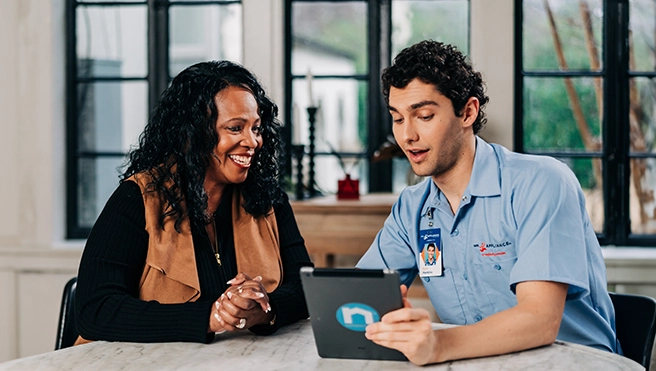 A Mr. Appliance technician talking with a client while sitting at a table.