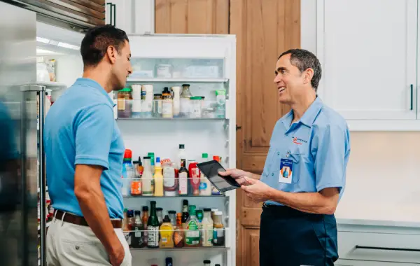A Mr. Appliance service professional assists a homeowner with smart refrigerator repairs.
