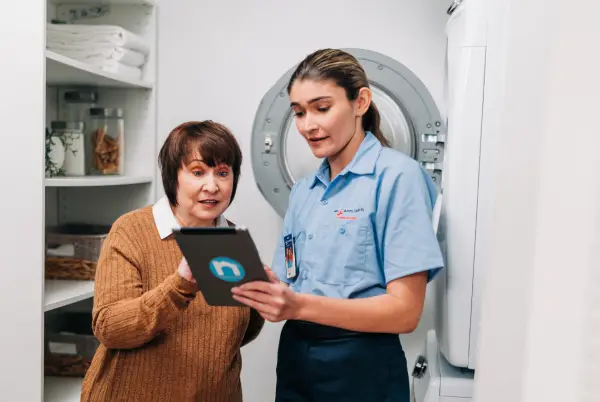 A Mr. Appliance service professional helping a homeowner with laundry room repairs.