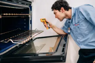 A Mr. Appliance service professional repairing an oven