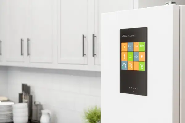 A smart refrigerator with a digital door display in a white, modern kitchen.