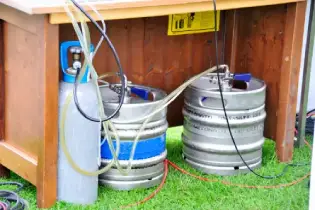 Two metal beer kegs under a table and hooked up to a kegerator system.